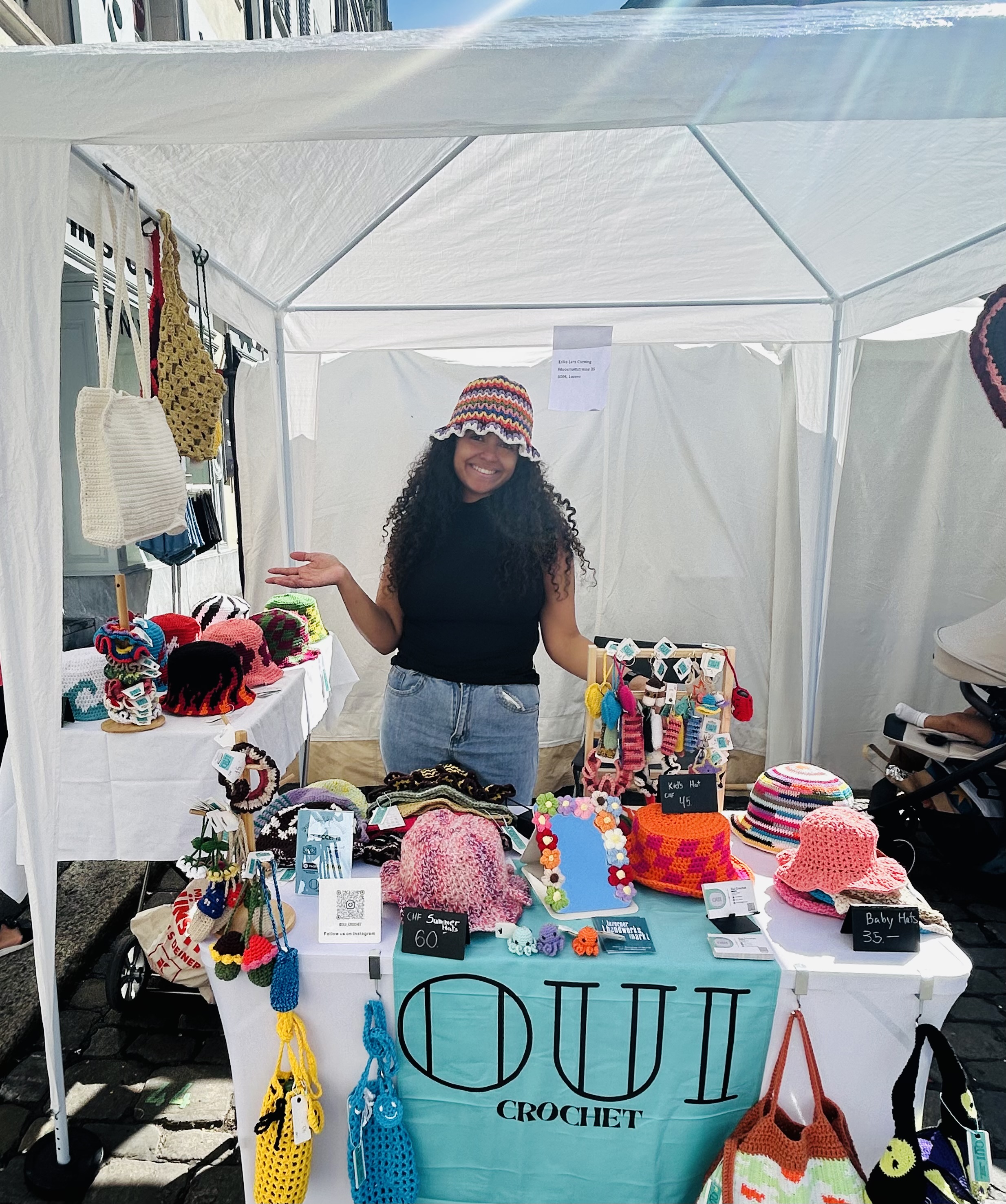 Erika at her OUI Crochet market booth displaying colorful handmade crochet items